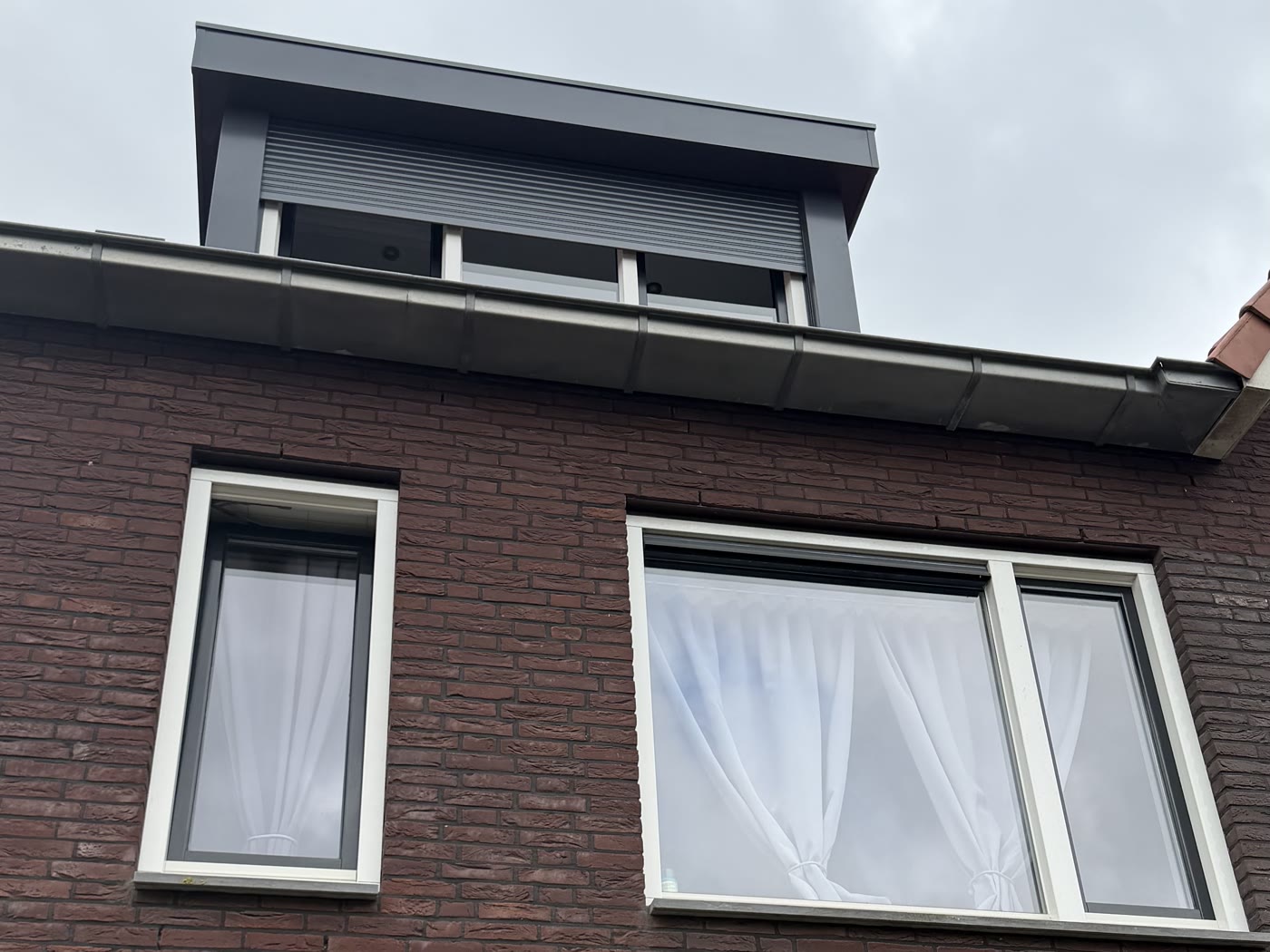 Voorgevel van een rijwoning zonder rolluiken op de eerste verdieping