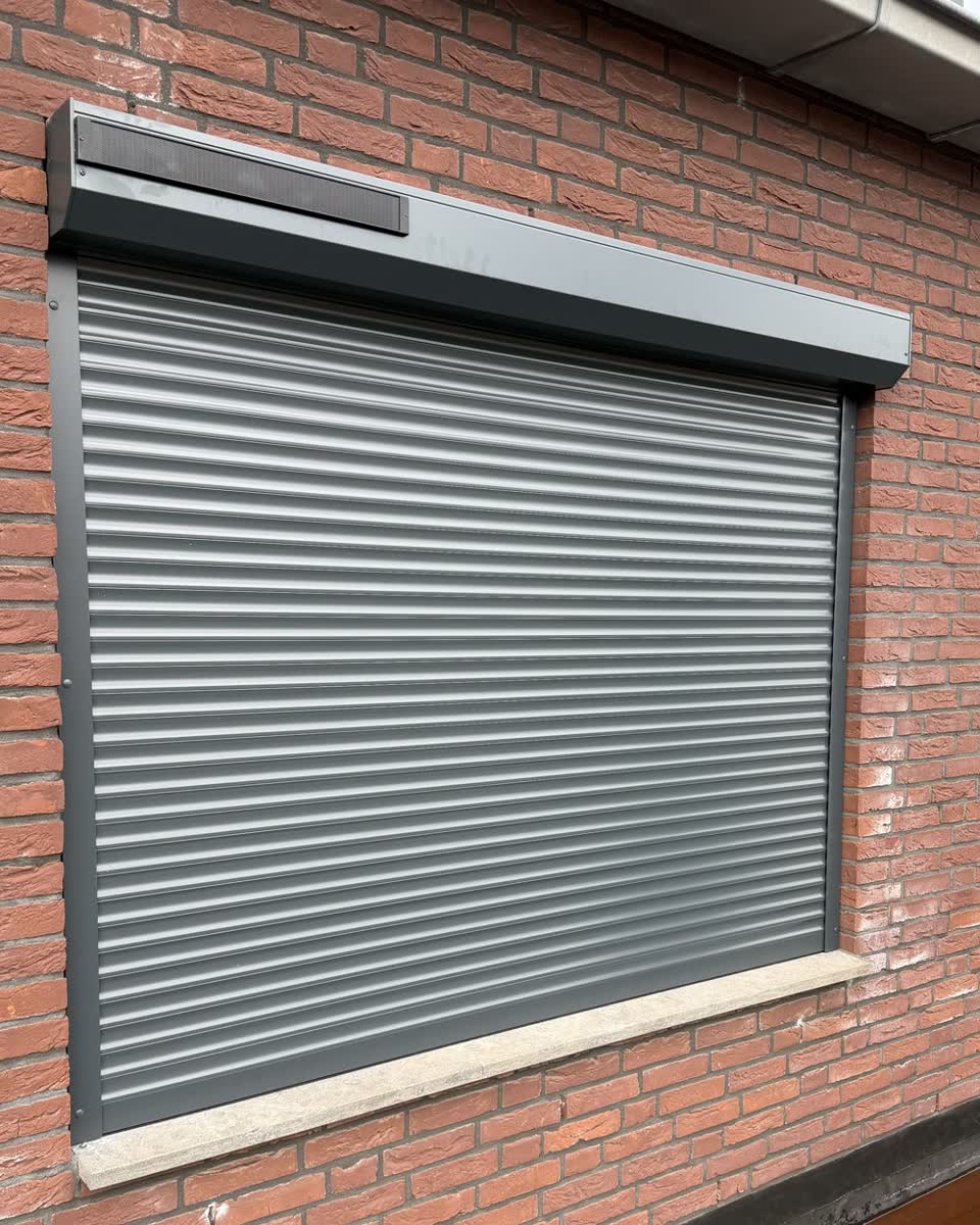 Gesloten antraciet solar rolluik in een bakstenen achtergevel